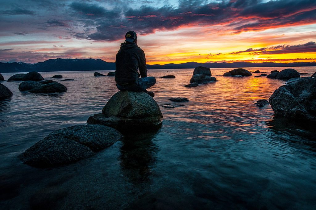 person sitting on rock on body of water 14786852 scaled