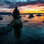 person sitting on rock on body of water 14786852 scaled