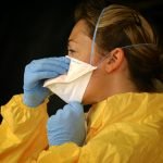 woman in yellow protective suit wearing white face mask 39929481 scaled