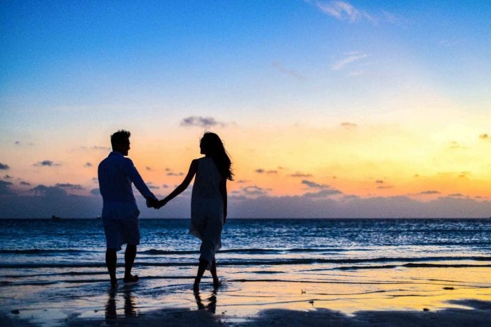 man and woman holding hands walking on seashore during 1024960 scaled