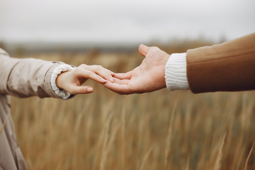 young couple holding hands gently in field 4241312 scaled